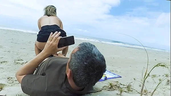 Vacationers look on with disapproval as a milf with her BF films anal content right on the beach
