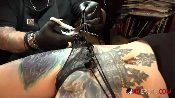 Marie Bossette touches herself while being tattooed