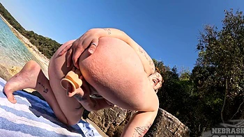 A blonde beauty with big boobs plays with a dildo on the peaches beach.